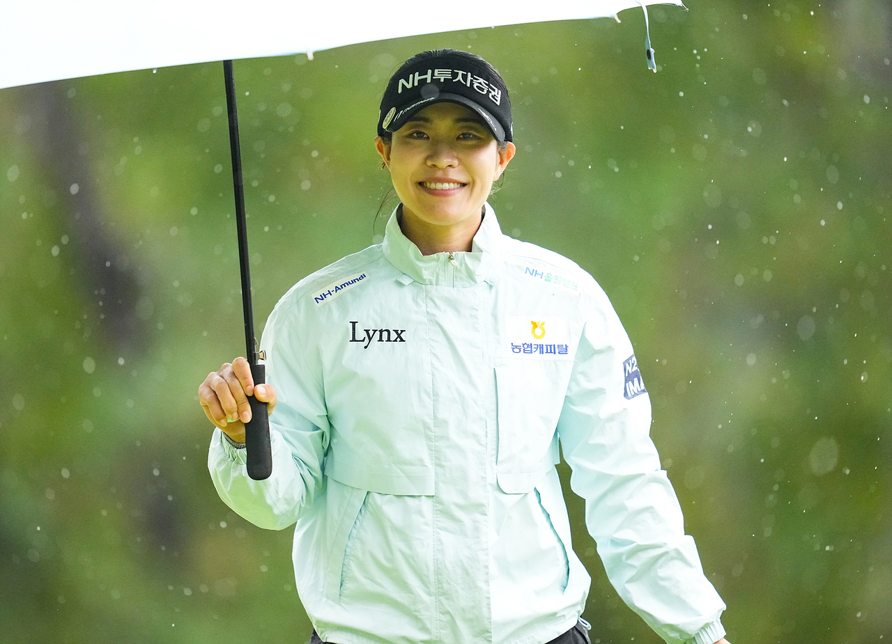 박민지가 24일 전남 해남군 파인비치 골프 링크스에서 열린 LPGA 투어 BMW 레이디스 챔피언십 3라운드 1번 홀에서 버디에 성공한 뒤 우산을 쓰고 이동하며 활짝 웃고 있다. [대회 조직위 제공]