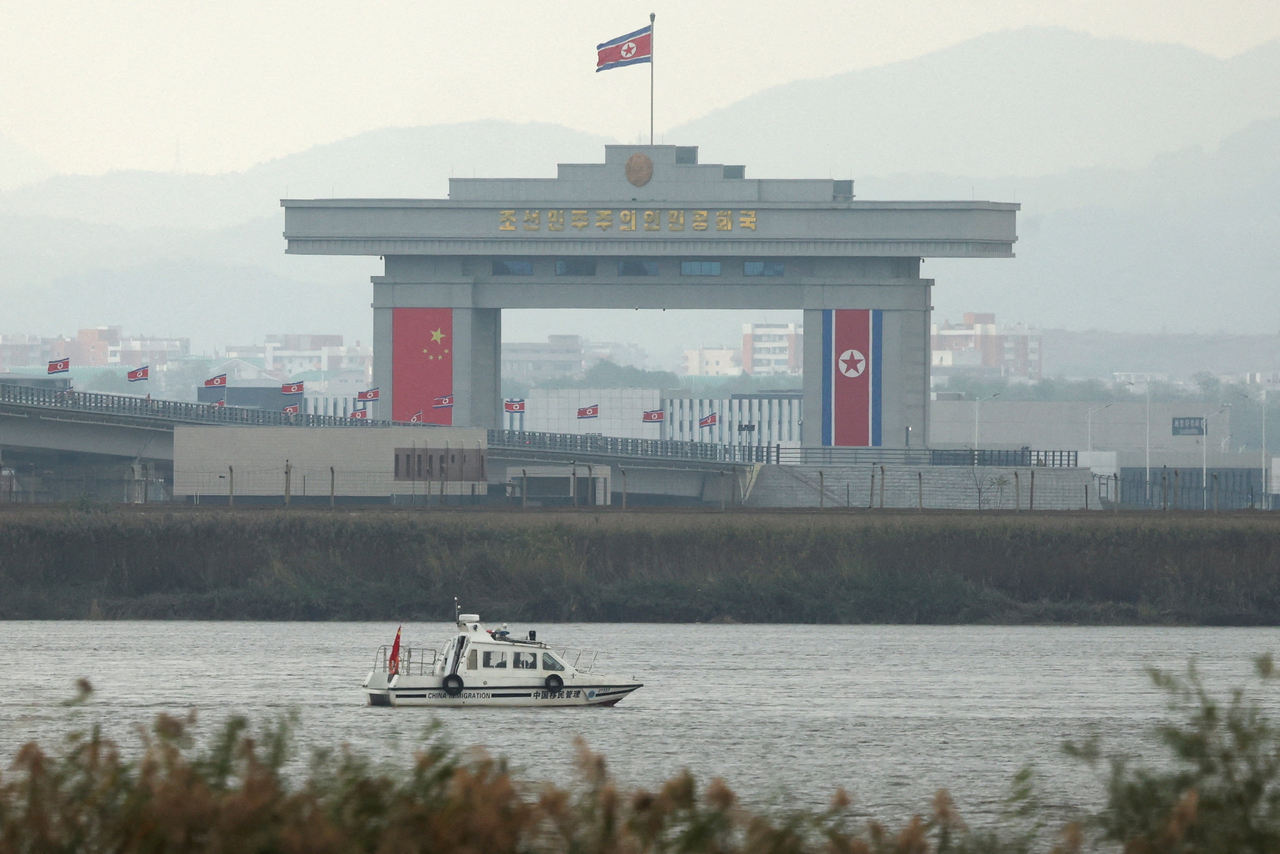 A China Immigration inspection vessel travels along the Yalu river past a North Korean customs building at the end of the newly opened New Yalu River Bridge, which connects North Korea's Sinuiju from China's Dandong New Zone, as seen from Dandong, Liaoning province, China October 15. (Reuters-Yonhap)