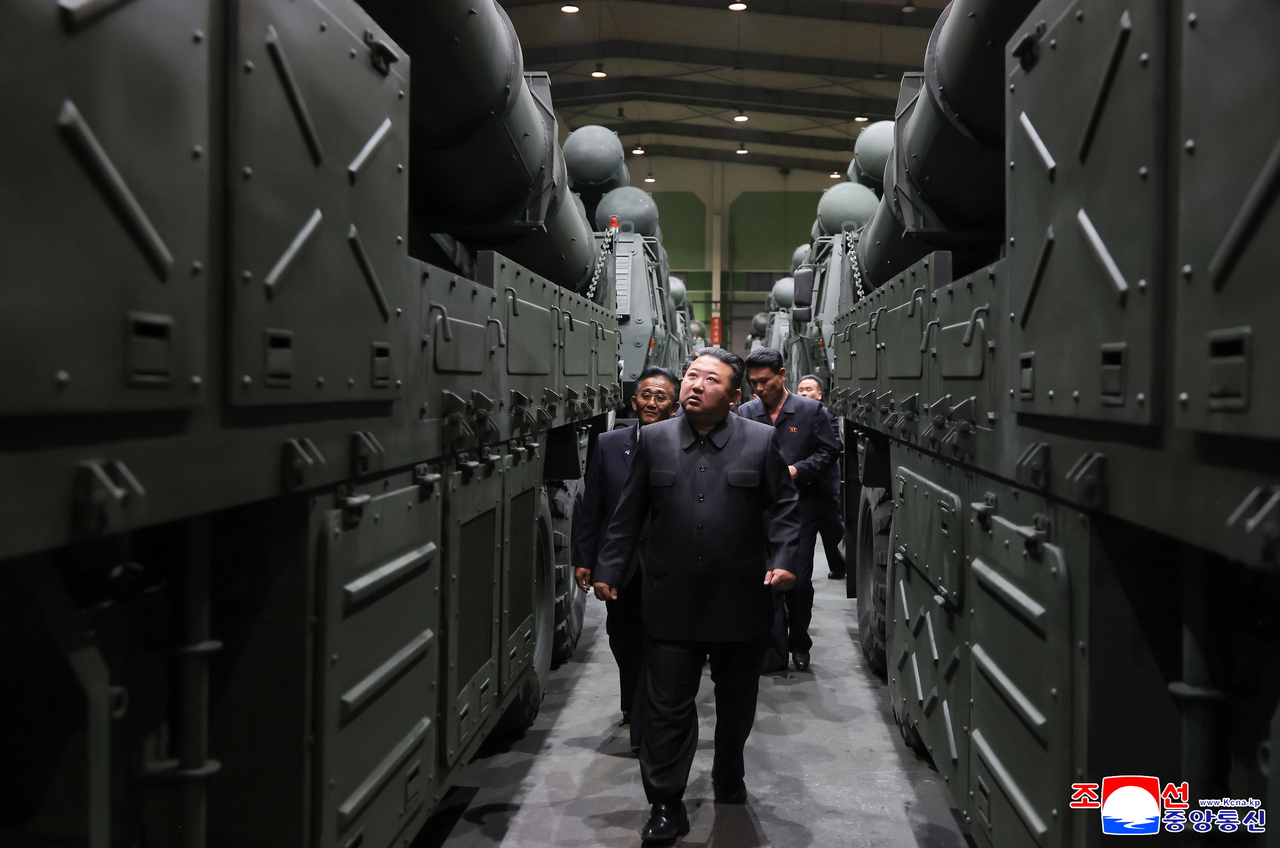An undated photo released by the official North Korean Central News Agency (KCNA) shows North Korean leader Kim Jong-un (center) discussing the production of major munitions during a tour of a munitions factory with officials from the defense science research sector, in an undisclosed location in North Korea.  (EPA-Yonhap)