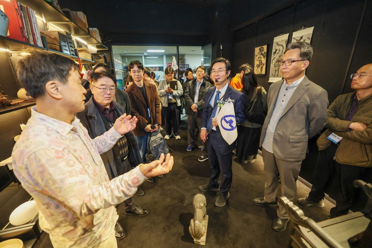 답십리고미술상가를 찾아 점주로 부터 설명을 듣는 최동민 동대문구청장(오른쪽 세번째 깃발 든 사람)