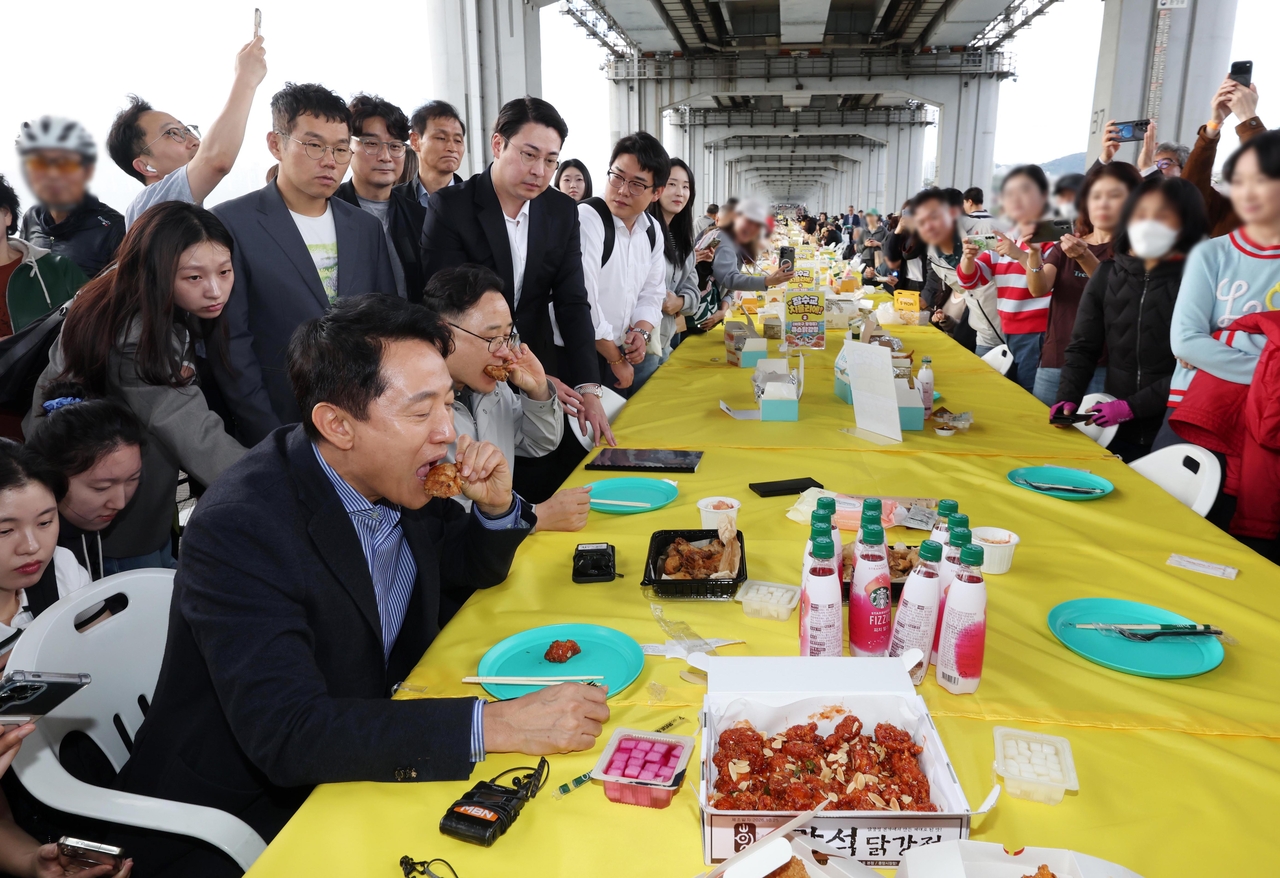 Seoul Mayor Oh Se-hoon (left) samples fried chicken during Jamsu Bridge Chicken Day on the bridge in Seocho-gu, Seoul, Sunday. (Joint Press Corps via Yonhap)