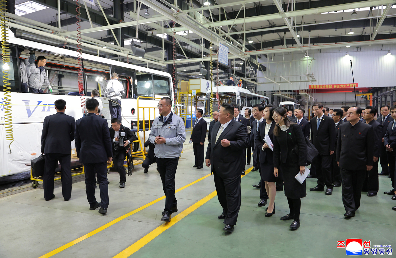 A factory representative (left) shows North Korean leader Kim Jong-un (center) around an automobile factory in Dandong, Liaoning province, on Oct. 24. (KCNA)