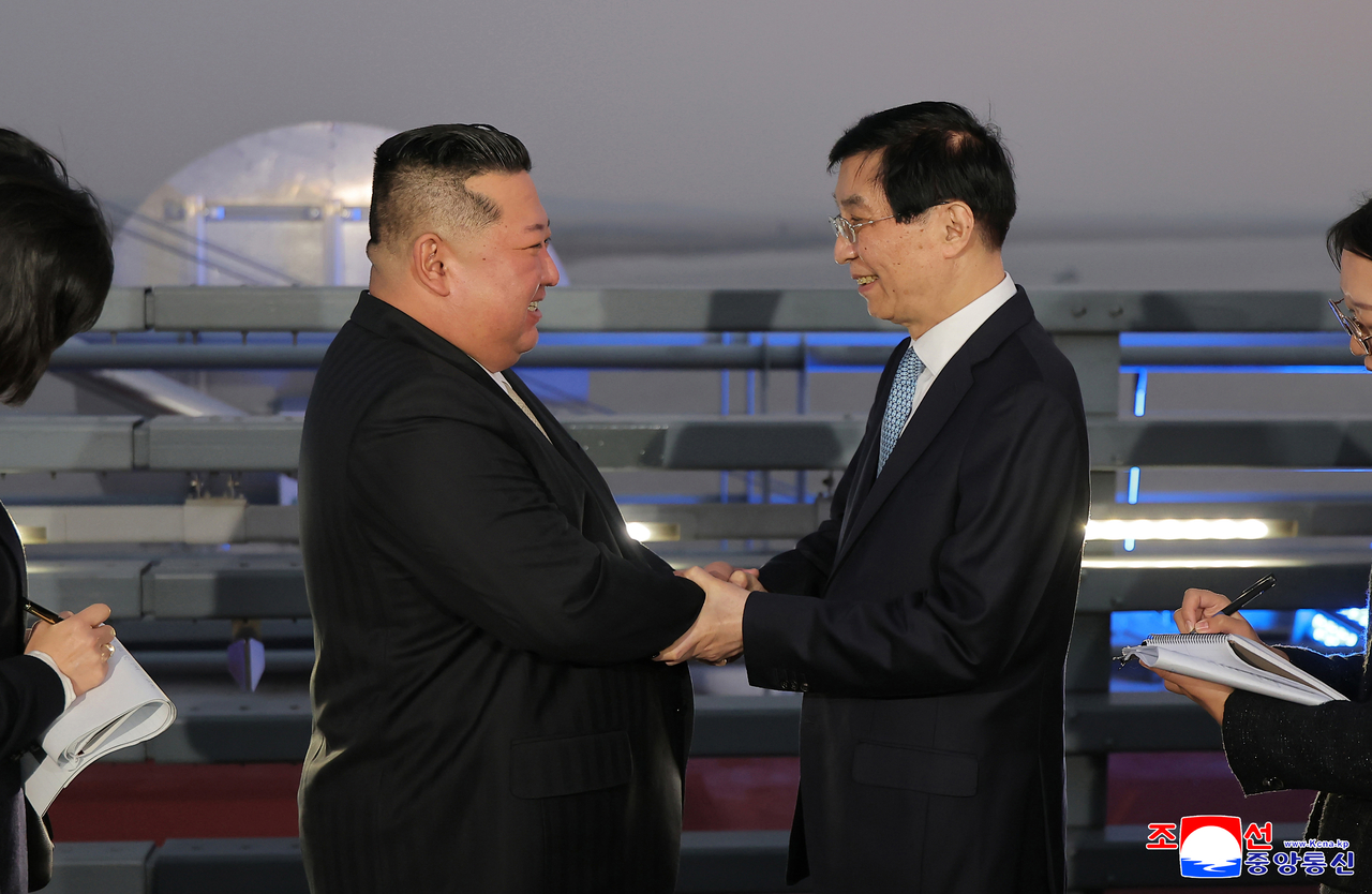 North Korean leader Kim Jong-un (right) shakes hands with Wang Huning, chairman of China's top political advisory body, during his visit to Dandong, Liaoning province, on Oct. 24. (KCNA)