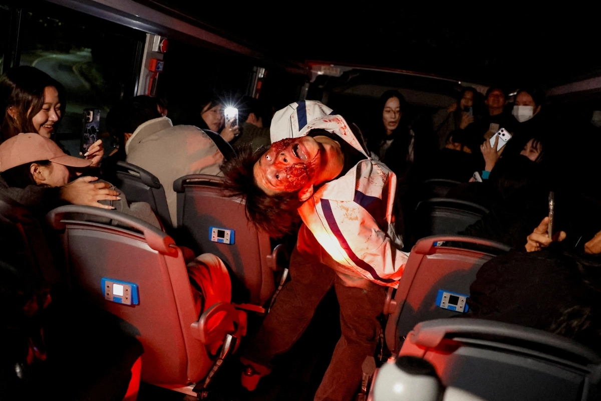 Passengers take photos of performers covered in fake blood and dressed as zombies aboard a sightseeing bus during a zombie-themed program operated by Seoul City Tour Bus on Oct. 20. (Yonhap)