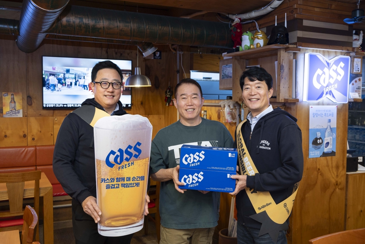 OB Beer Executive Vice President Koo Ja-bum (left) and Sales Vice President Kim Byung-hoon (right) present a beer glass bearing a responsible drinking message to a restaurant owner on Global Beer Responsible Day. [OB Beer]