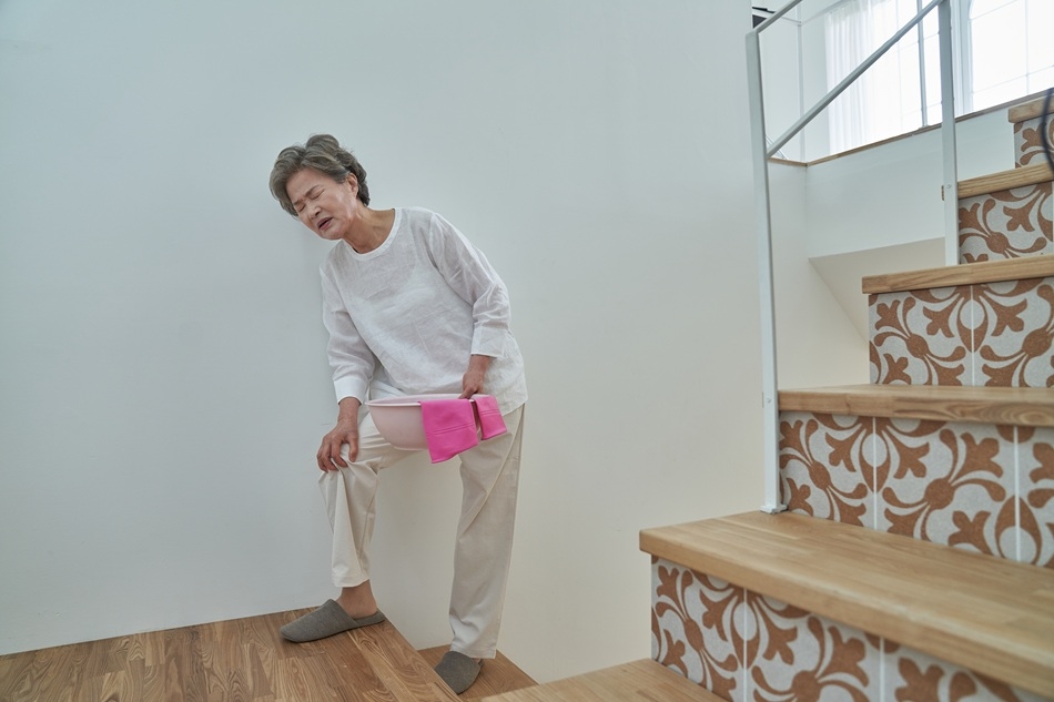A senior holds her knee in pain while climbing stairs. (Getty Images Bank)
