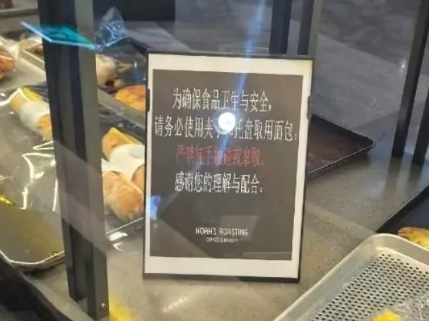빵 진열대 사이에 맨손으로 빵을 만지거나 집는 것을 금지한다는 내용의 중국어 안내문이 세워져 있다. 보배드림 캡쳐]