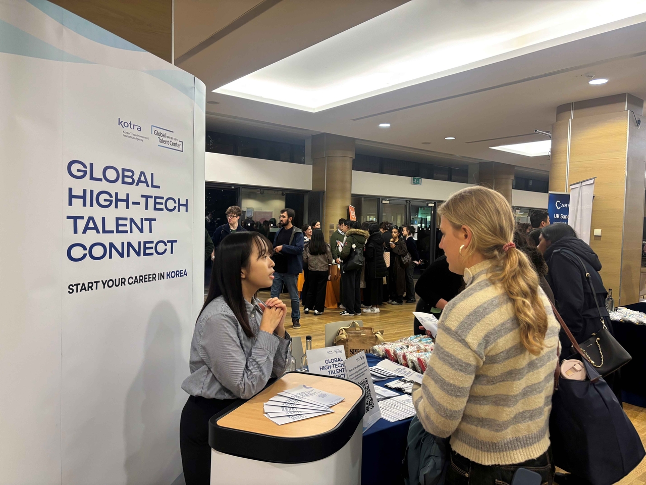 A local job seeker reviews information on employment opportunities in South Korea at a KOTRA promotional booth and consults with an official.