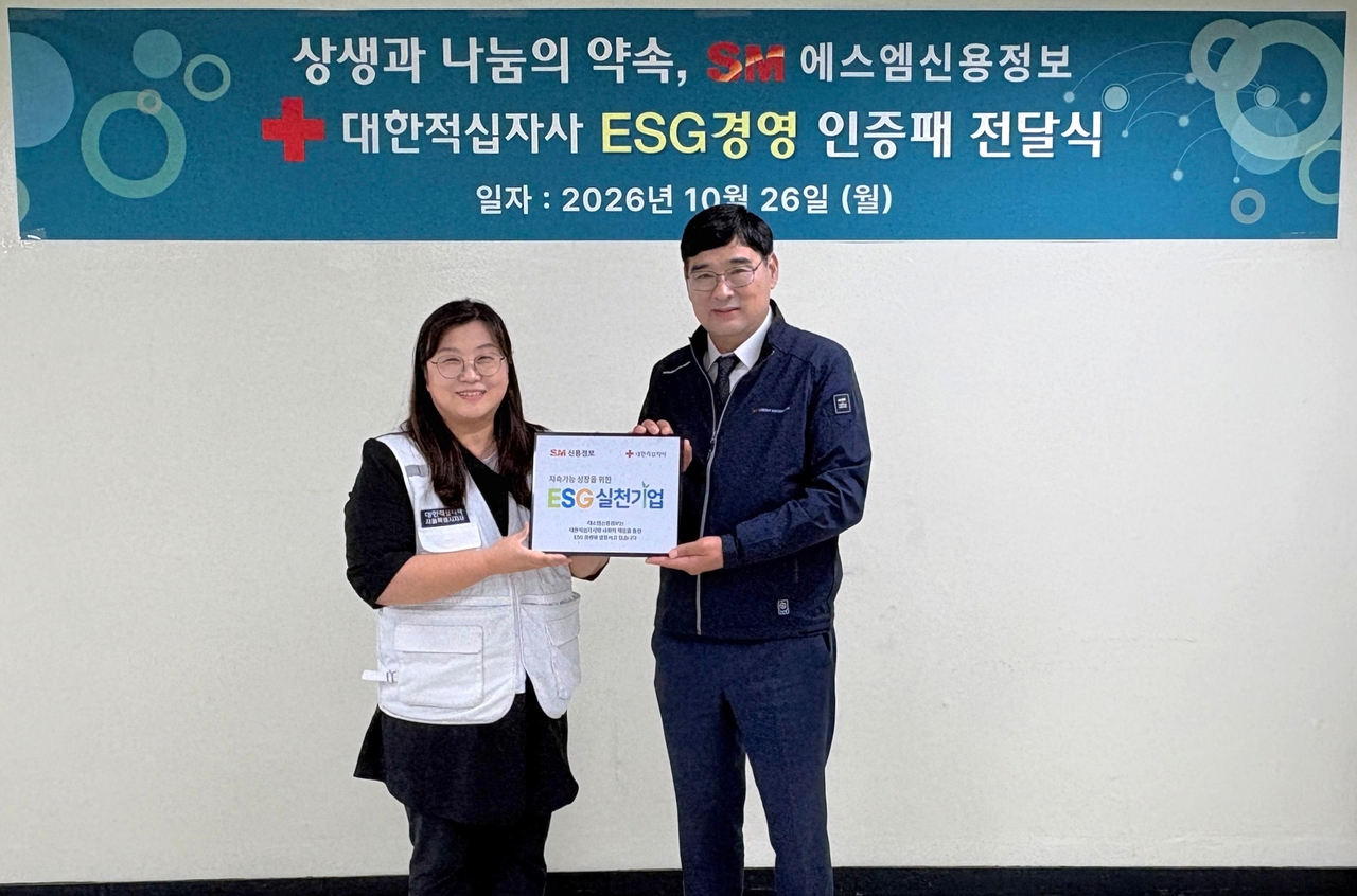 SM Credit Information CEO Gong Moon-yong (right) poses for a photo after receiving the Korean Red Cross "ESG Practice Company" certification plaque from Kim In-suk, head of the sharing planning team, at a ceremony held Monday at the company's headquarters in Yeongdeungpo-gu, Seoul. [Provided by SM Group]