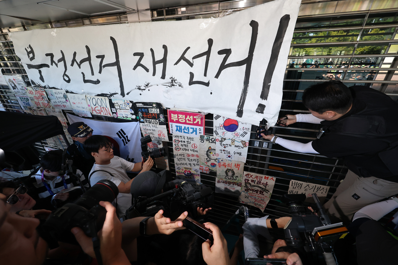 Police remove signs alleging election fraud and calling for a rerun of the election as they enter the Olympic Park Handball Gymnasium in Seoul’s Songpa-gu on Sept. 8, amid protests that blocked access to the Jamsil vote-counting center following a ballot shortage during the June 3 local elections. (Yonhap)