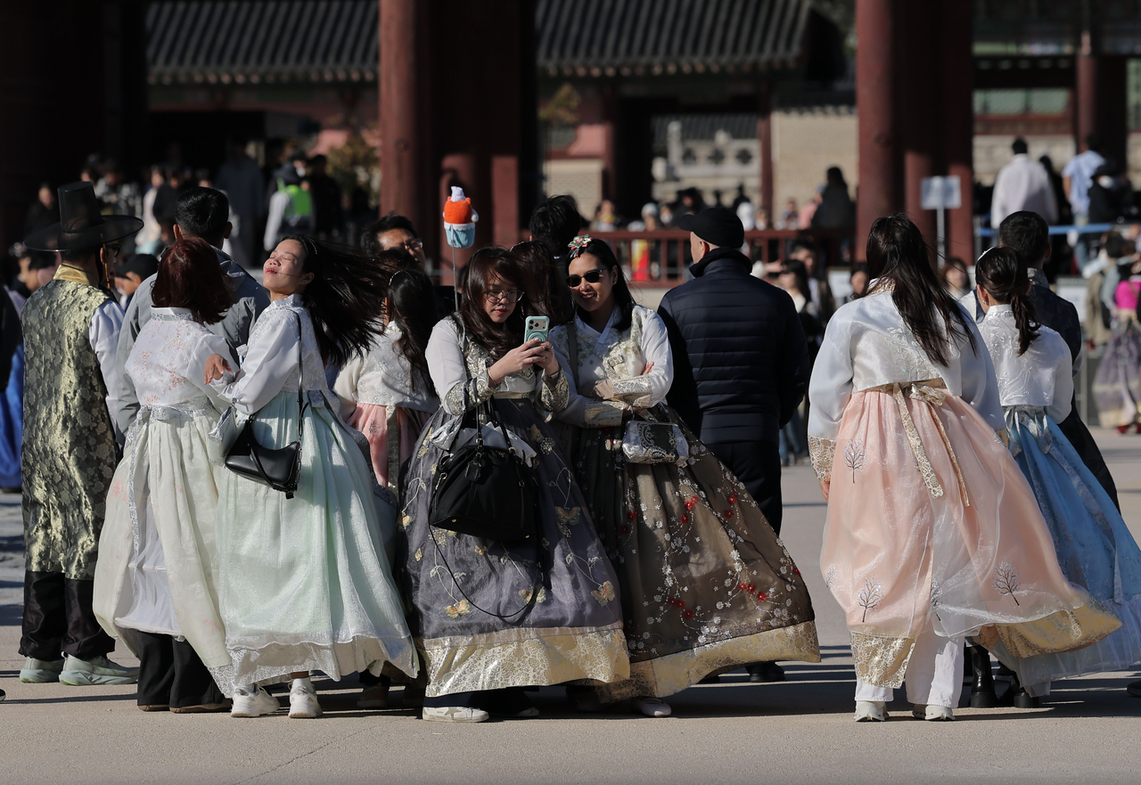Tourists walk against the wind at Gyeongbokgung in Seoul on Oct. 21.  (Yonhap)