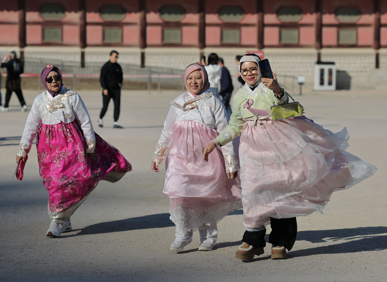 Tourists walk against the wind at Gyeongbokgung in Seoul on Oct. 21.  (Yonhap)