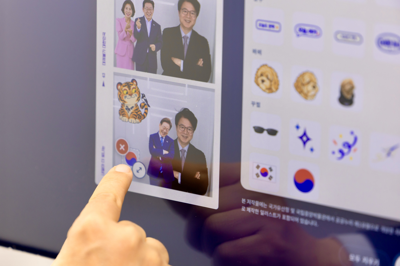 The screen of an interactive photo booth at Cheong Wa Dae shows photo frames featuring President Lee Jae Myung and the presidential couple, among other options. The free booth allows visitors to take photos and download them to their smartphones. (Yonhap)