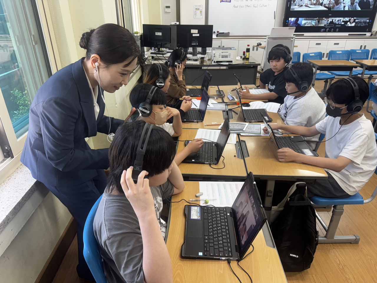 Seoul Beondong Elementary School English teacher Jeon Yu-jin (second from left) helps students during small-group discussions with their peers in Indonesia and Japan as part of a virtual international joint class at the school in Seongbuk-gu on Tuesday. (Lee Seung-ku/The Korea Herald)