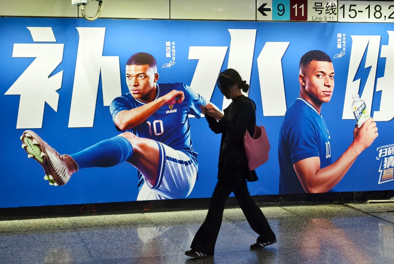 A woman walks by an advertisement featuring soccer star Kylian Mbappe in Shanghai, June 30.   (AP-Yonhap)