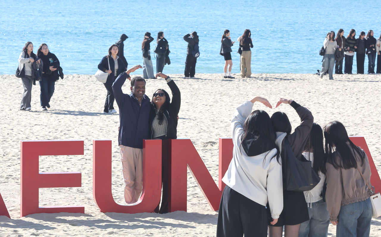 Tourists pose for photos at Haeundae Beach in Busan on Wednesday. (Yonhap)