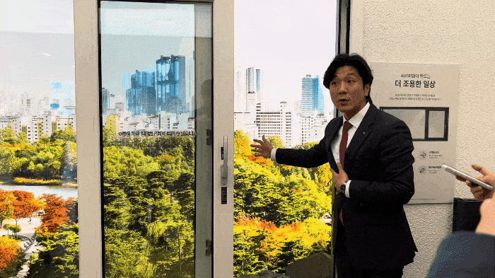 An IPark Hyundai Development official demonstrates the aircraft noise-blocking effect of triple-pane windows at the Mokdong IPark Lounge on the seventh floor of Hyeonjun Plaza in Guro-gu, Seoul, on Wednesday. (Kim Hee-ryang)
