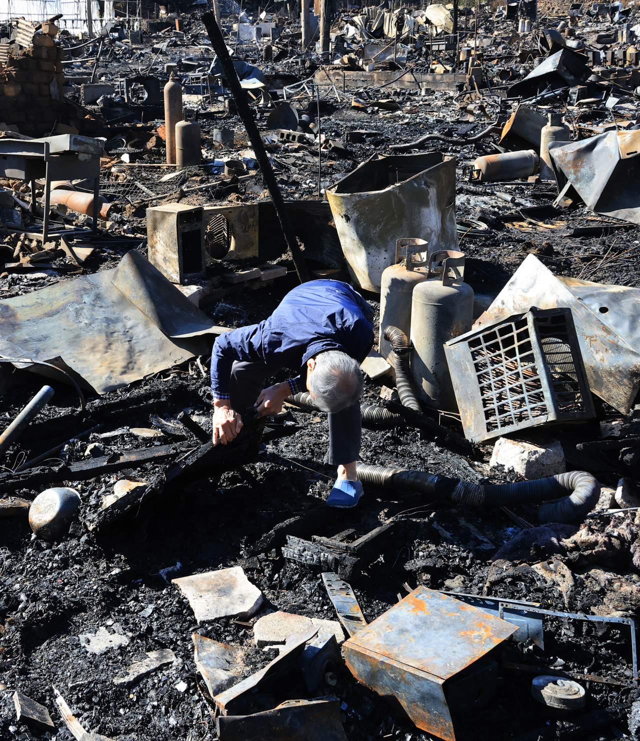 A resident searches for belongings in the remains of their home in Guryong Village in Gangnam-gu, southern Seoul, on Wednesday, after a fire swept through the village on Tuesday. (Yonhap)
