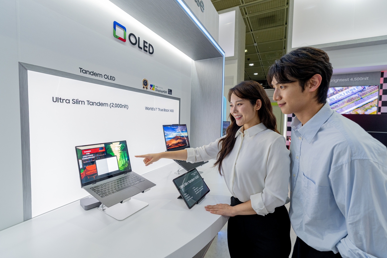 Visitors examine Samsung Display's tandem OLED screens for laptops at K-Display 2026 in Seoul in July. (Samsung Display)