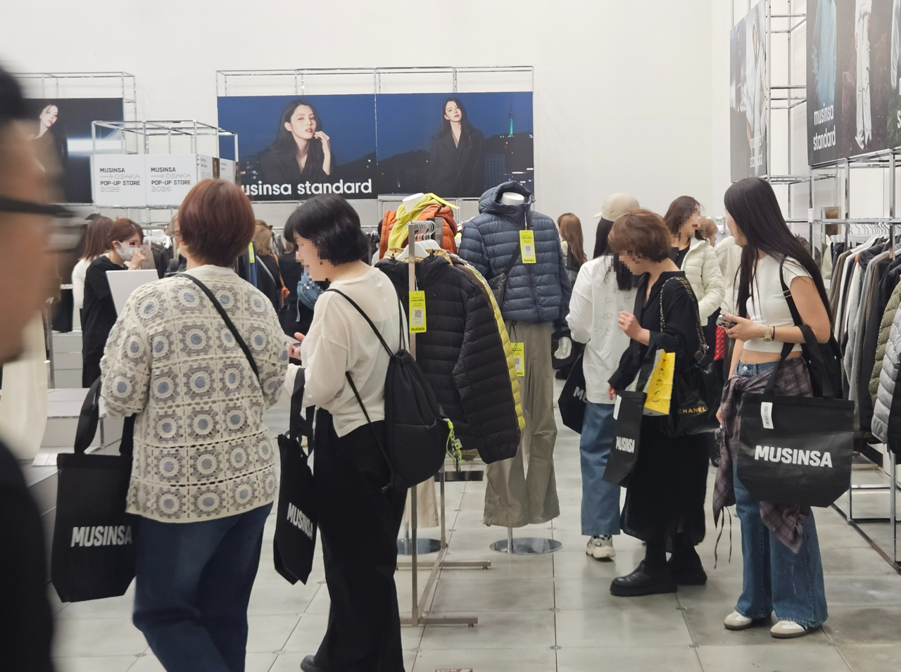 지난 23일(현지시간) 일본 오사카에서 열린 무신사의 팝업스토어 내 ‘무신사 스탠다드’ 전시관에서 현지 방문객들이 옷을 구경하고 있다. [김진 기자]