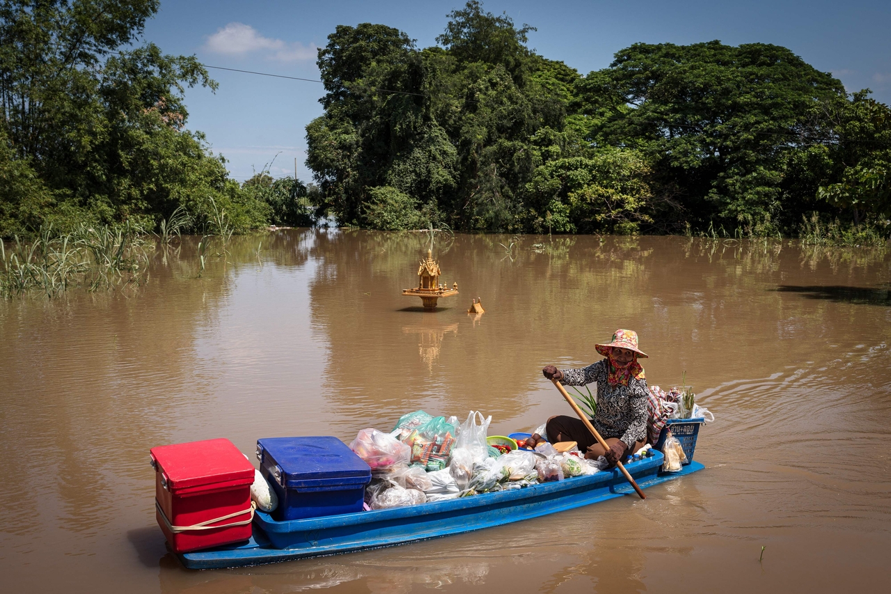 A vendor sells prepared food from her boat as she paddles past a flooded spirit house in Sena district in the central Thai province of Ayutthaya, Oct. 7. (AFP-Yonhap)