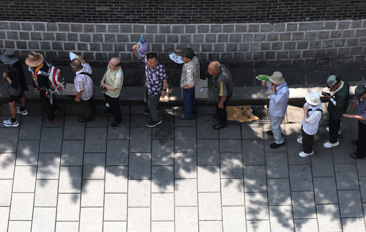 Older adults line up for free meals near Tapgol Park in Jongno-gu, Seoul, on Aug. 3. (Yonhap)