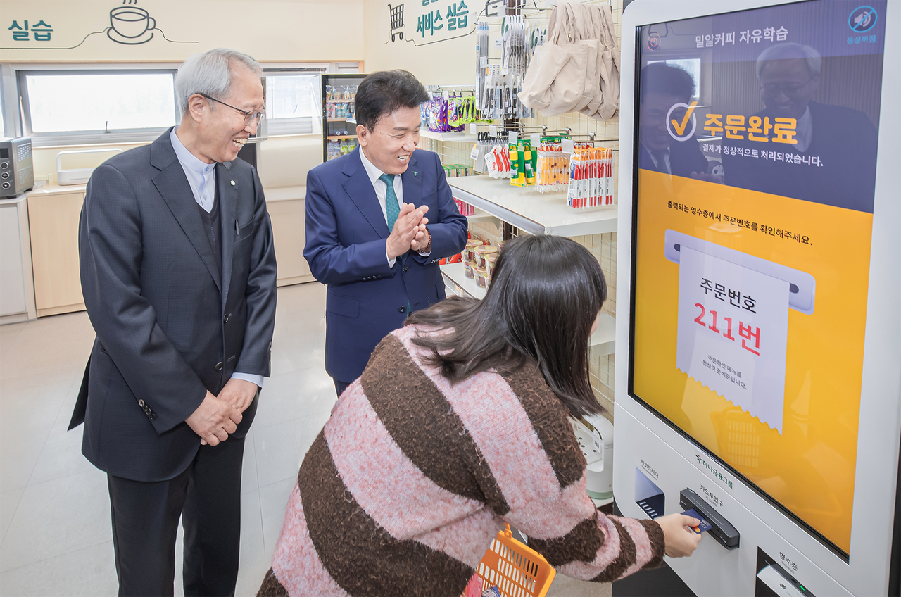 Hana Financial Group Chairman Ham Young-joo (center) watches a student practice using a self-service kiosk at a digital vocational training classroom at Miral School in Gangnam-gu, southern Seoul, Tuesday. (Hana Financial Group)