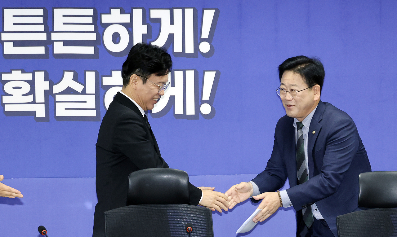 Labor Minister Kim Young-hoon (left) and Rep. Kim Jung-ho, chair of the parliamentary Environment and Labor Committee, shake hands at the National Assembly in Seoul on Thursday. (Yonhap)