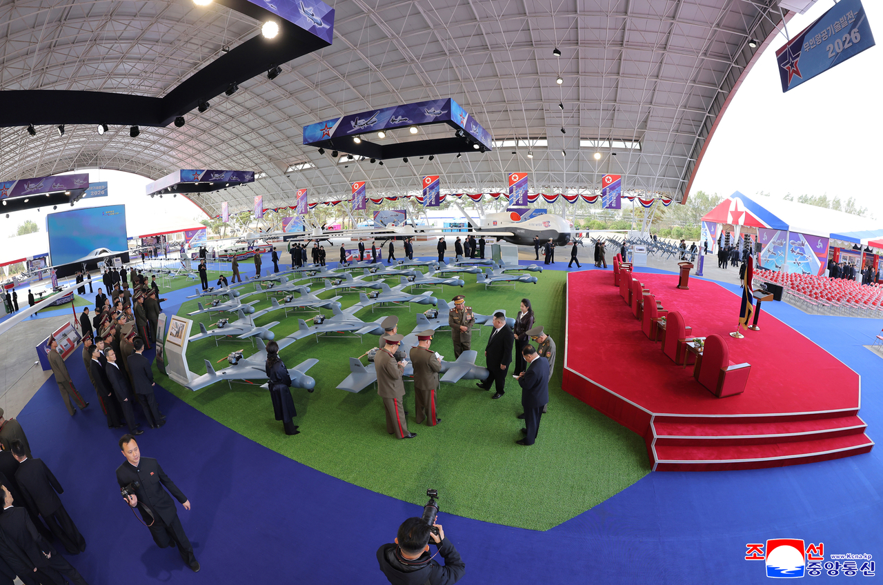 North Korean leader Kim Jong-un examines a drone alongside military officials at the “Unmanned Aviation Technology Development 2026” exhibition on Thursday in this photo released by the Korean Central News Agency on Friday. (Yonhap)
