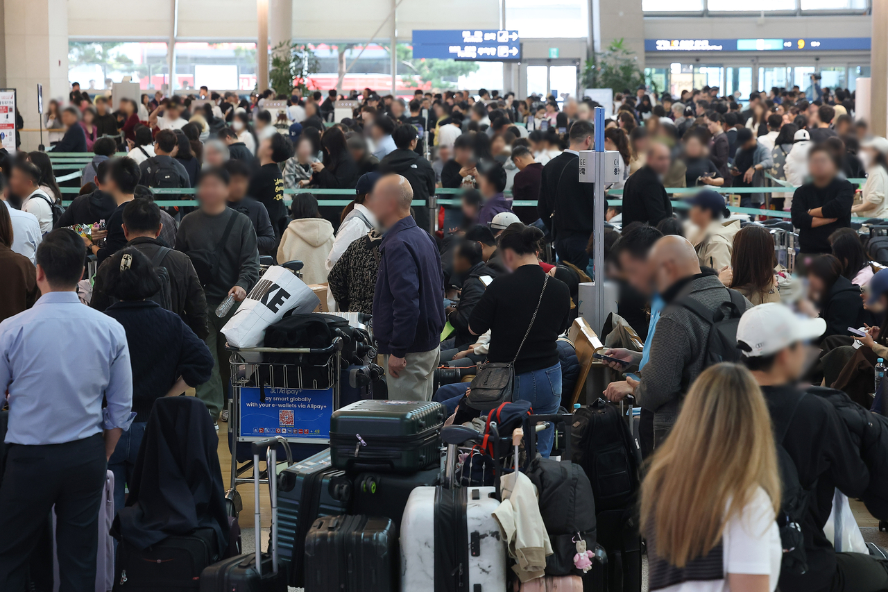 Passengers wait in line at a check-in counter at Incheon Airport amid network disruptions on Friday. (Yonhap)