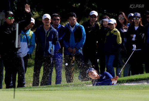 5번홀 벙커샷을 하는 전인지와 파란색의 옷을 입고 관전하는 갤러리. [사진=KLPGA]