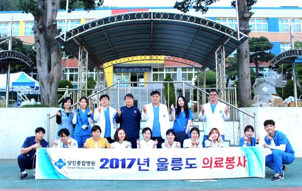 전우진(뒷줄 오른쪽 세번째)당진 종합병원장과 의료진이 울릉초등학교에서 의료봉사를 마치고 손가락으로 사랑을 표시하며 기념촬영을 하고 있다.(병원 제공)