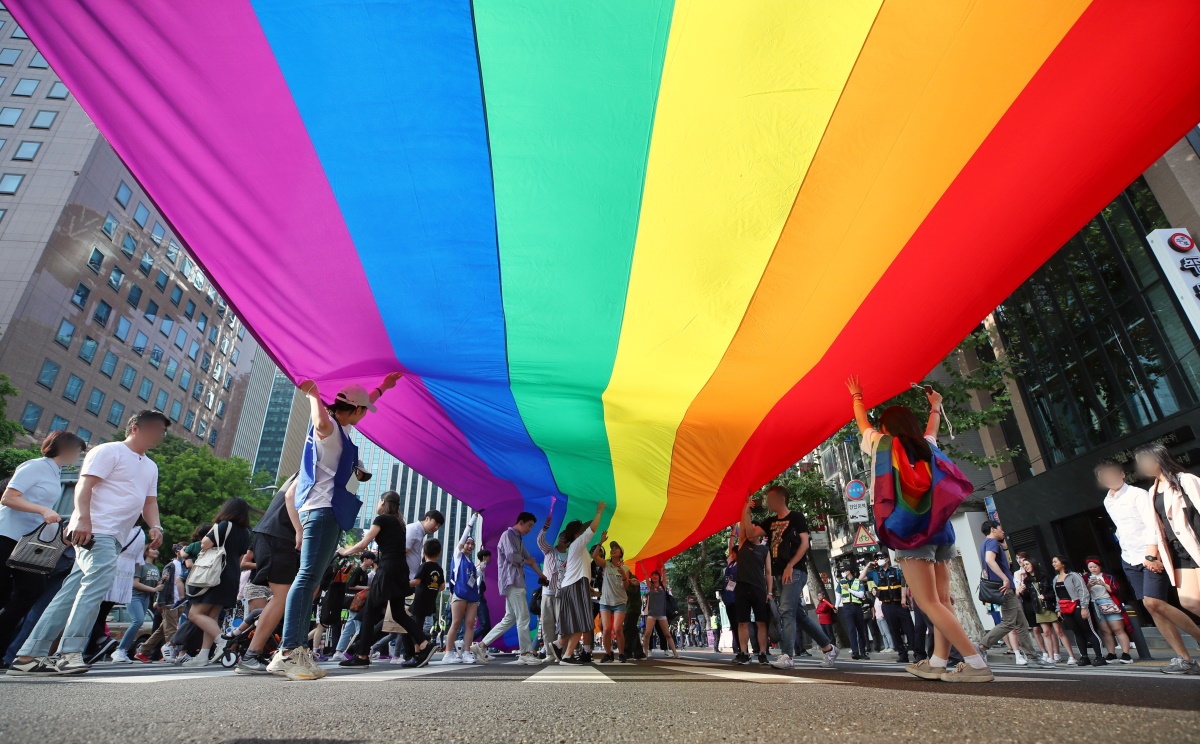 Pride-goers march under a rainbow flat in central Seoul on June 1. (Yonhap)