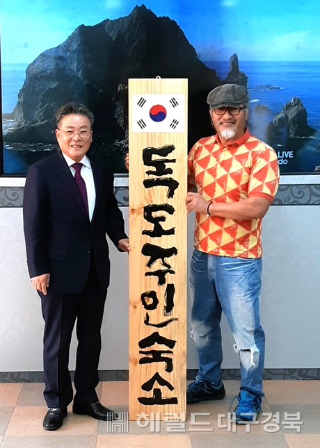 울릉군청을 방문한 서예가 쌍산 김동욱(어른쪽)씨가 김병수 울릉군수에게  자신이 만든 독도주민숙소 현판을 선보이고 있다.