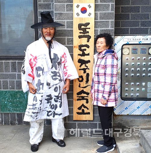 쌍산 김동욱씨(왼쪽)가 독도주민 김신열씨에게 새로운 독도주민숙소 현판을 제작해 전달하고 있다.