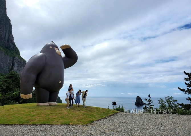 추산(송곳산)을 닮은 고릴라 캐릭터인 울라와 공암을 배경으로 사진을 찍고 있는 관광객들(헤럴드 DB)