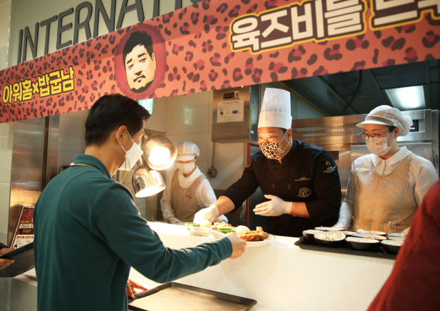지난 20일 아워홈이 운영하는 여의도 소재 구내식당에서 열린 ‘아워홈 플렉스 테이블’ 이벤트에서 유튜버 ‘밥굽남’이 일일 조리사로 변신해 고객에게 돈마호크카츠 메뉴를 배식하고 있다. [아워홈 제공]
