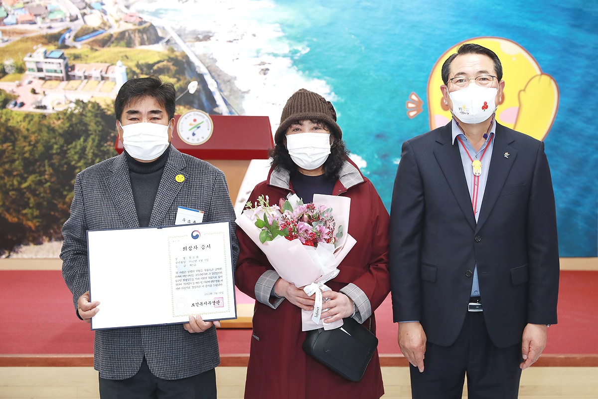 울진군1호 의상자로 선정된 우소춘(왼쪽)씨가 부인과 함께 전찬걸 울진군수로부터 의상자 증서를 받은뒤 기념사진을 찍고 있다(울진군 제공)