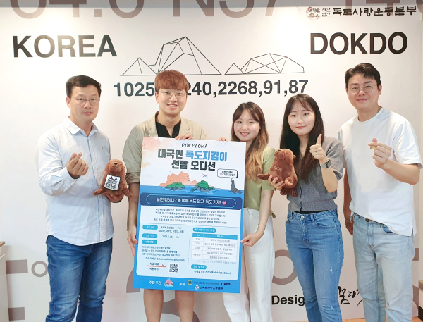 DOKPLOMA 학생들과 독도사랑운동본부 관계자들이  오디션 대형 포스터 를 들고 기념사진을 찍고 있다(독도사랑운동본부 제공)