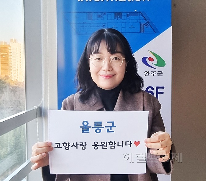 울릉군 '고향사랑 기부제' 1호 기부자인  전북 완주군청  유윤희 팀장이  "울릉군 고항사랑 응원합니다" 라는 글귀가 적힌   종이를 들고 있다.
