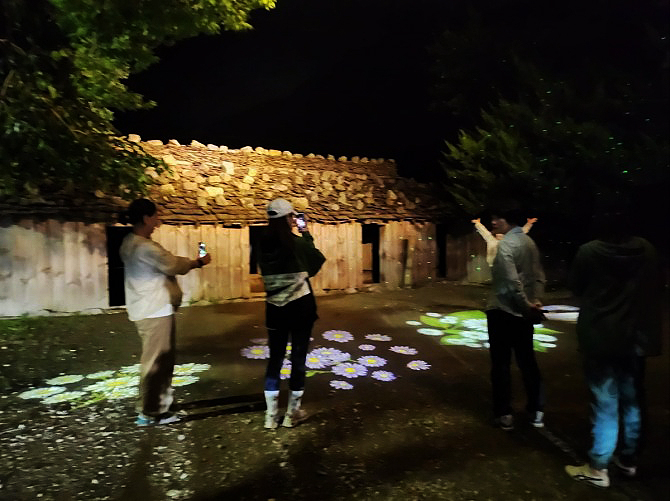 나리 빛나는 밤에 만나요'참가자들이 투막집 화려한 조명에서  사진을 찍고 있다(독자 제공)