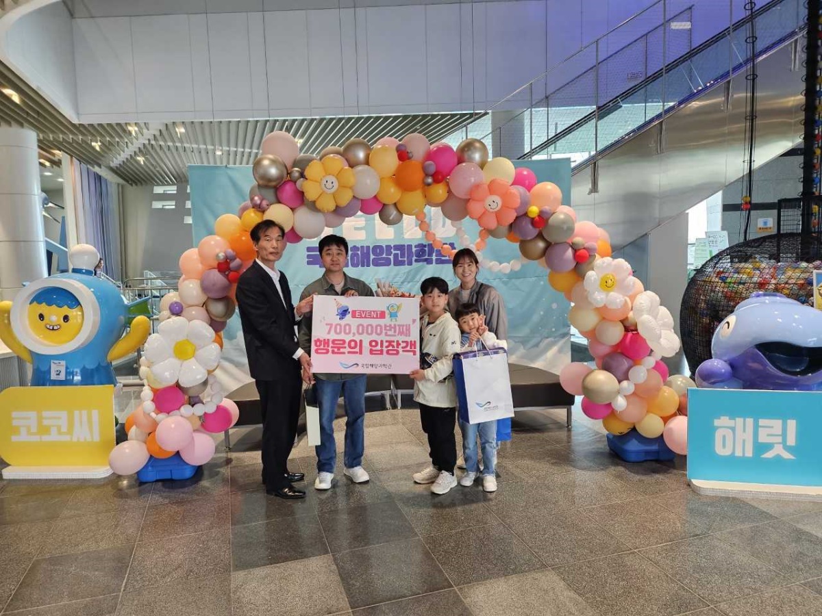 15일 김병곤(왼쪽) 과학관 경영지원본부장이 70만째 행운의 주인공에게 울진특산품과 꽃다발을 전달한후 기념사진을 찍고 있다(과학관 제공)