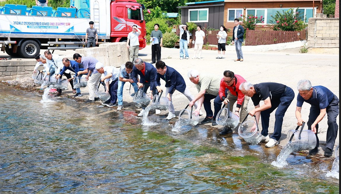 손병복 울진군수와 마을주민 관계자들이  어린 강도다리와  조피볼락을 방류하고 있다(울진군 제공)