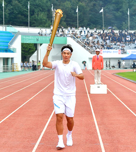 영주제일고등학교 박준선 선수가 많은 선수와 관중들이 지켜보는 가운데 성화를 들고 달리고 있다(영주시 제공)